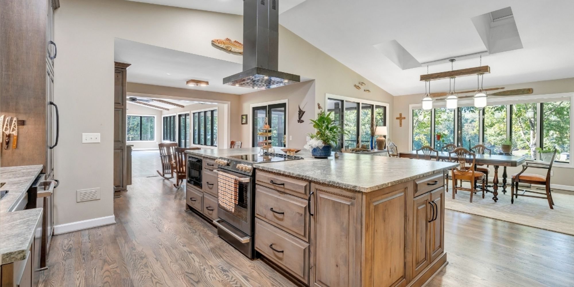 Open-concept kitchen inside a Roanoke home addition featuring tons of natural light, a large natural wood island, stone countertops, and dining area by Grace Alon Builders