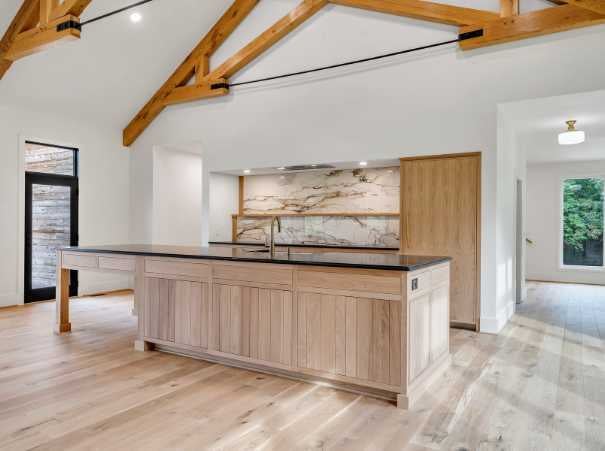 Kitchen in a custom home by Grace Alon Builders with exposed beams and waterfall island