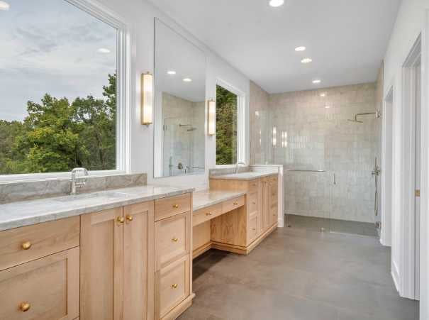 Custom primary bathroom by Grace Alon Builders featuring natural wood cabinetry and glass shower