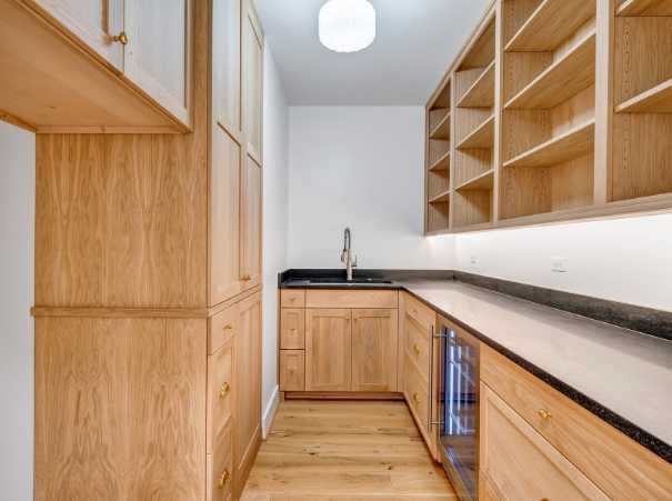 Hidden back kitchen by Grace Alon Builders with natural wood cabinetry and black countertops