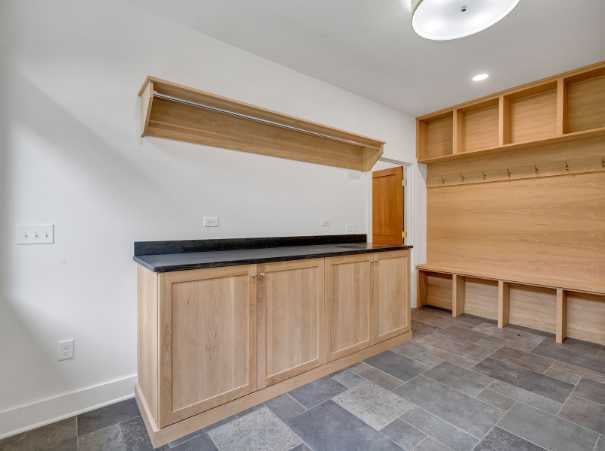 Practical mudroom and laundry combo with coat hooks and folding space by Grace Alon Builders