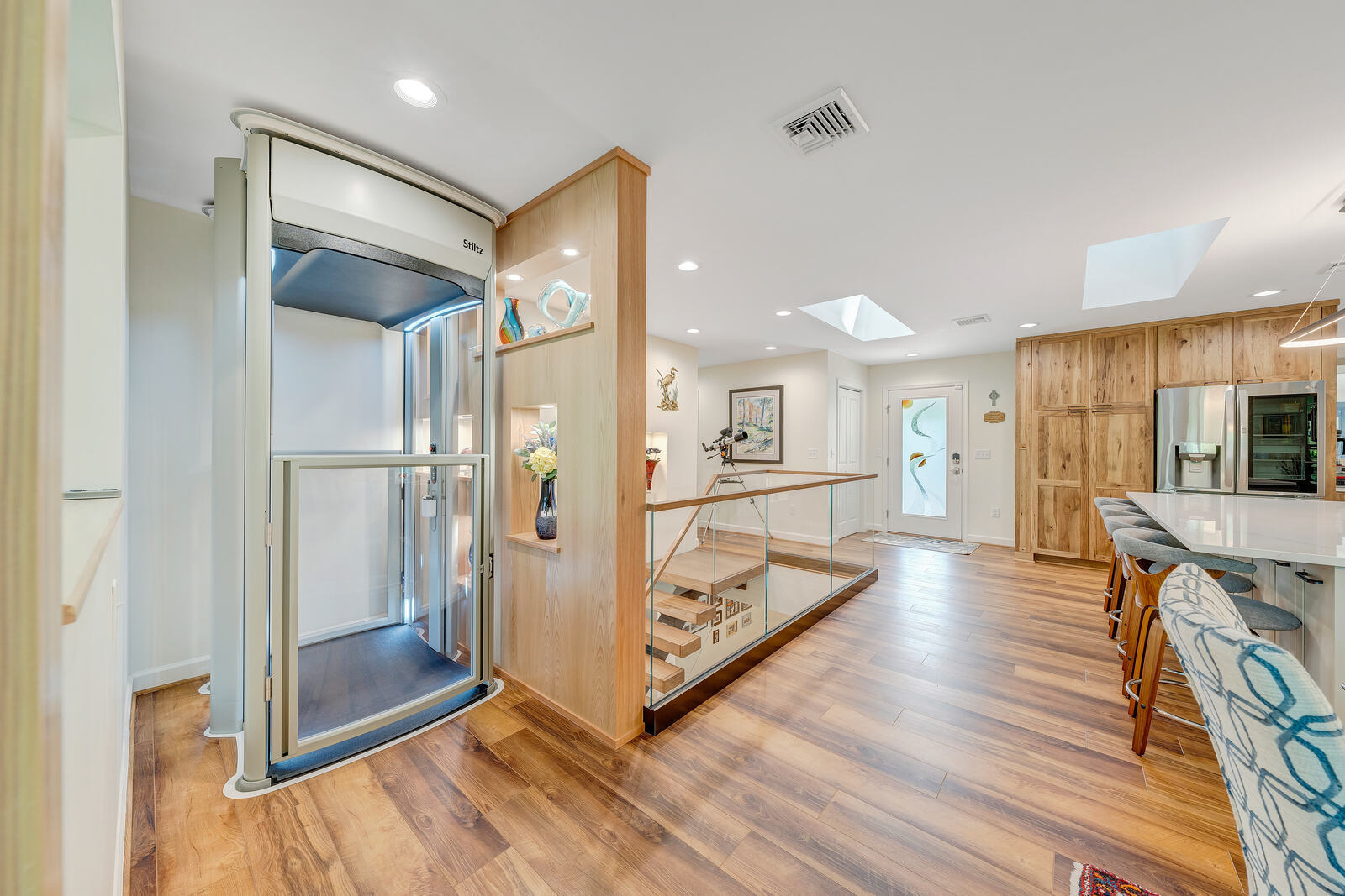 Grace Alon Builders-installed elevator in custom Smith Mountain Lake home next to stairwell and display shelving