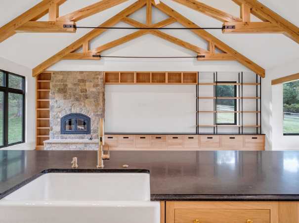 Open-concept view from the kitchen into the living room with stone fireplace by Grace Alon Builders