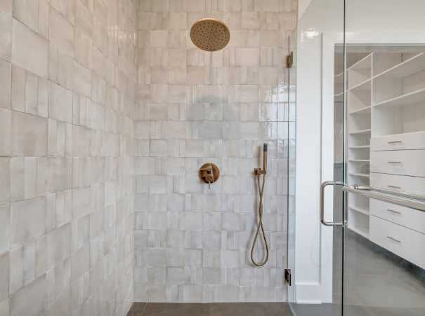 Custom bathroom shower featuring textured wall tile and built-in closet view by Grace Alon Builders